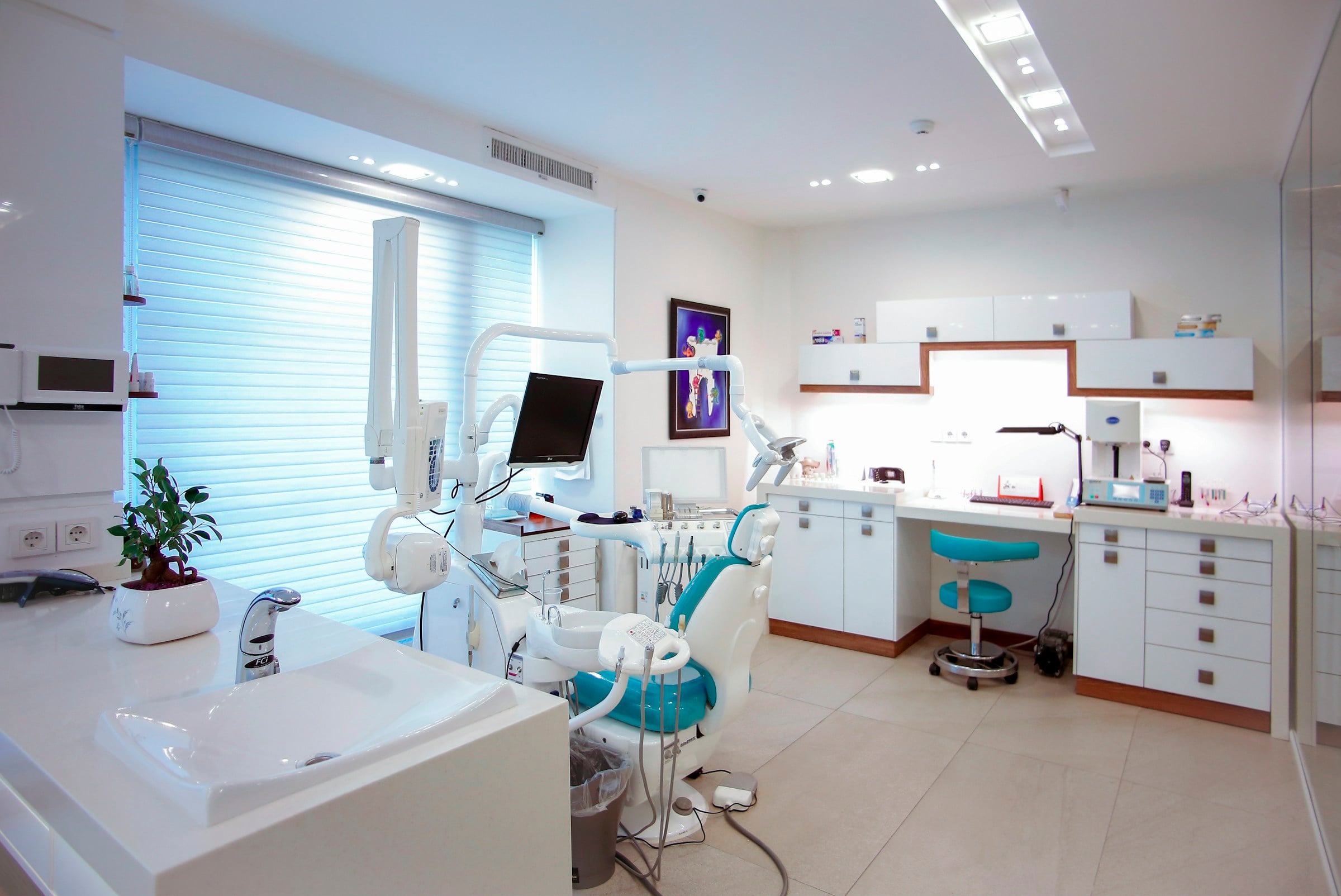 Bright, modern dental clinic with a white and teal treatment chair