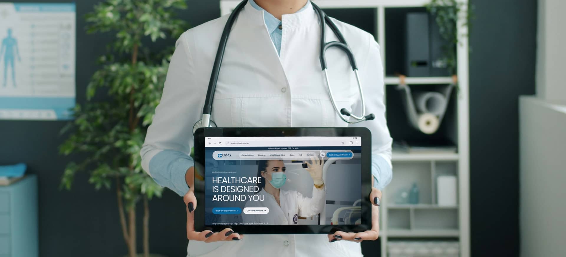 A doctor in a white coat and stethoscope holding up a tablet that shows the Essex Medical Care home page, “Healthcare is designed around you”