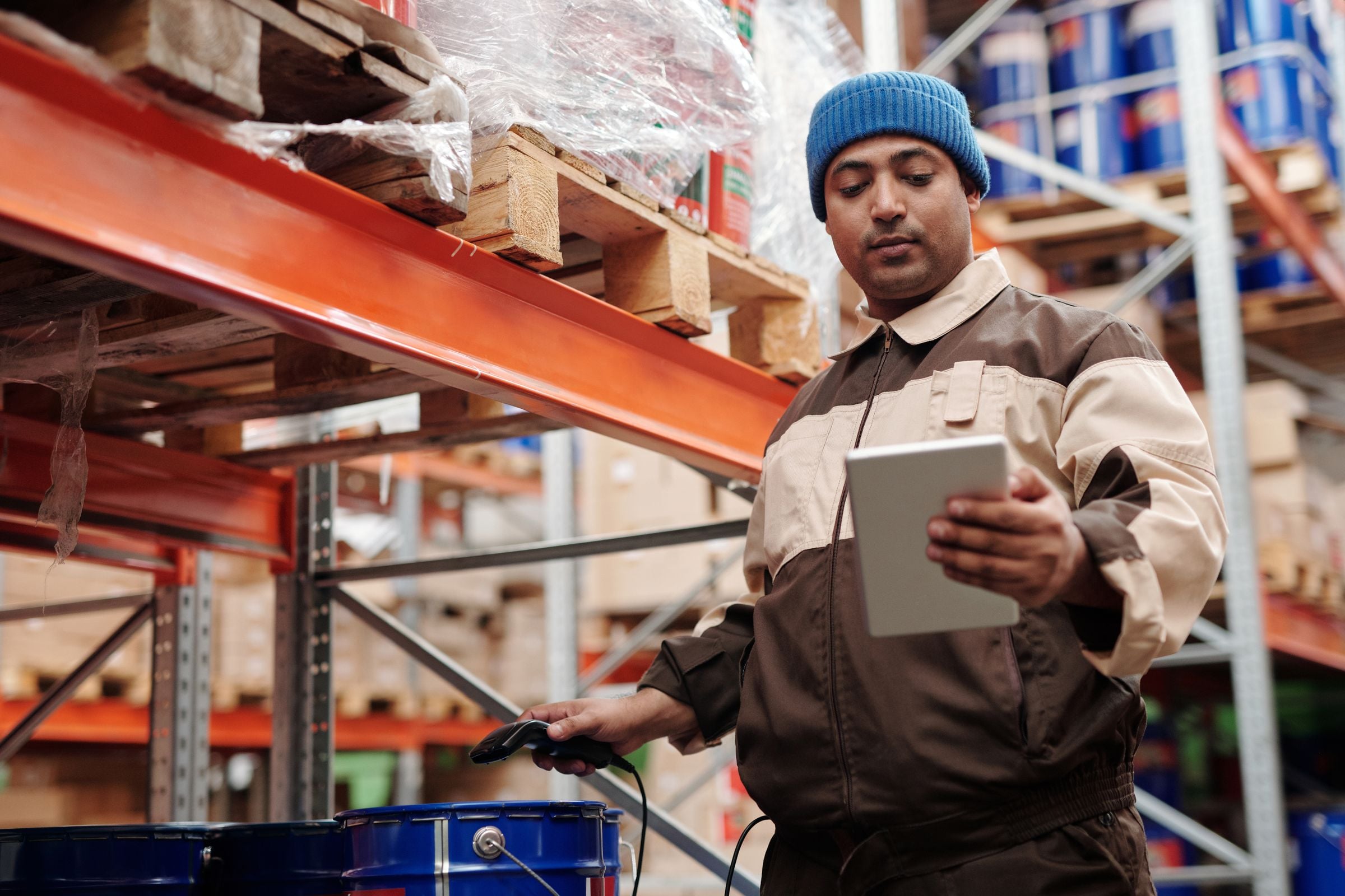 A warehouse worker checking stock on a tablet with a barcode scanner