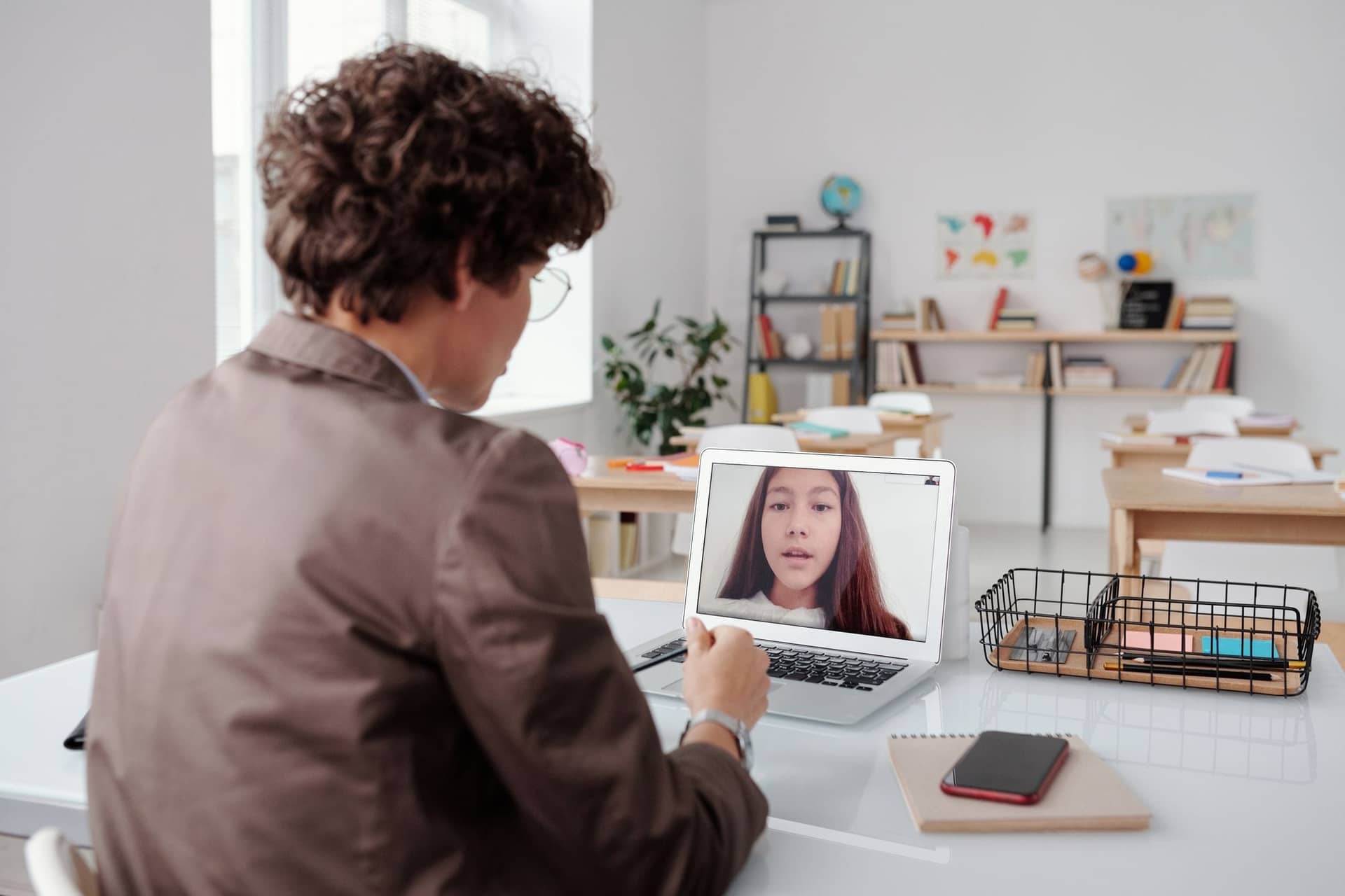 A tutor at a laptop teaching a student over a video call