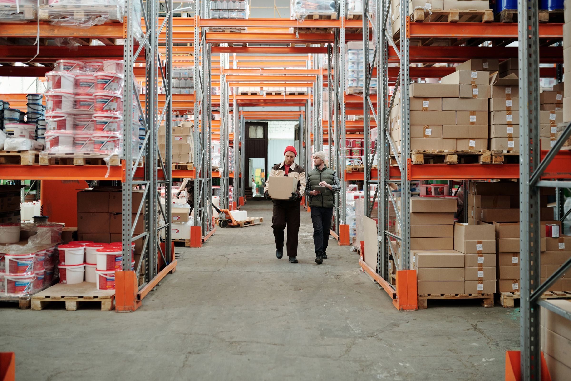 Two workers handling a package in a large warehouse
