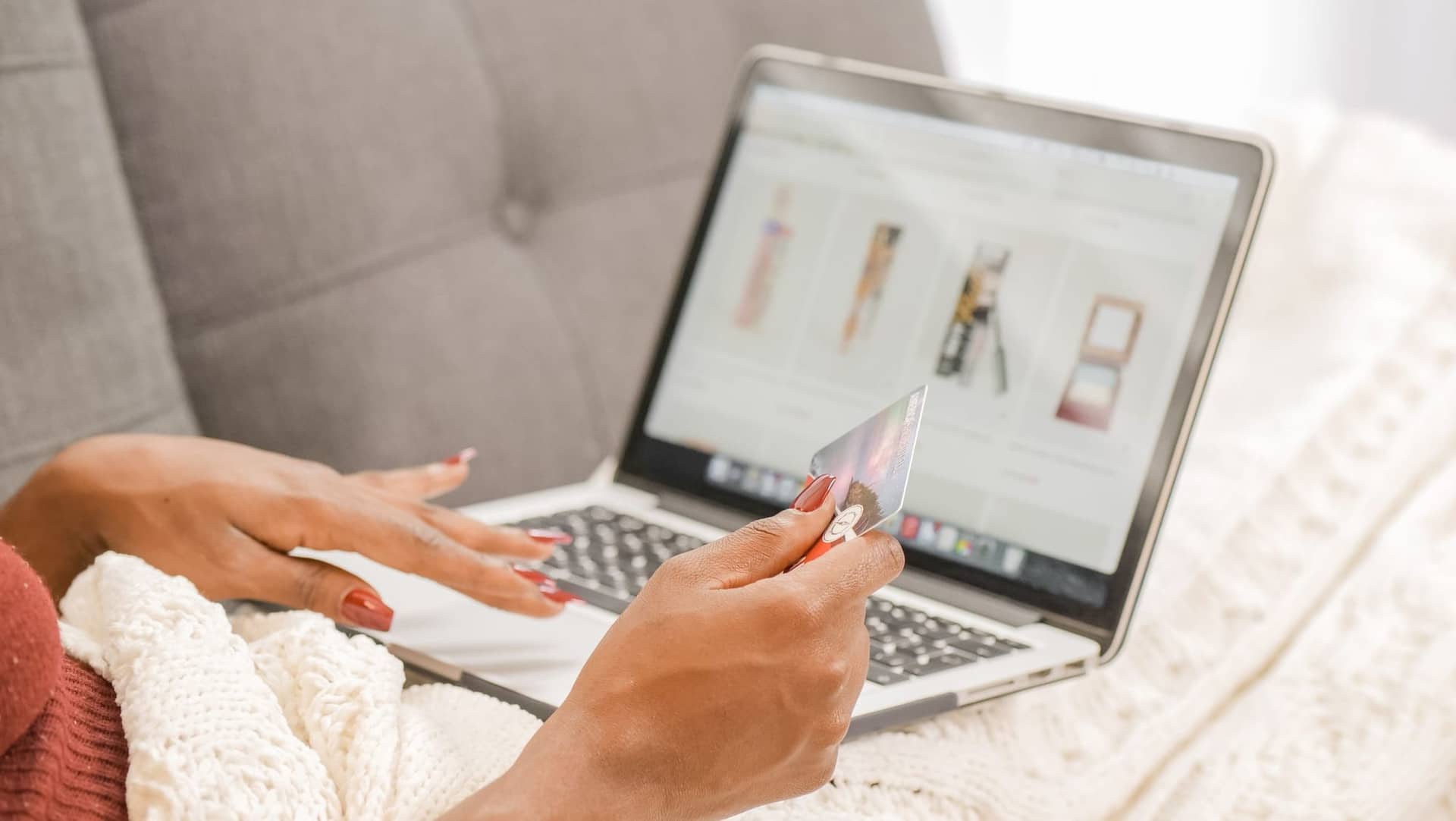 A woman shopping online on a laptop, holding a payment card